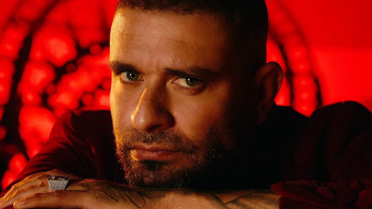 Artistas de diversos gêneros musicais se apresentam nos palcos da Semana de Arte do Rio, com shows variados e gratuitos. Close-up de homem barbudo com olhos verdes e anel no dedo, sob luz vermelha dramática