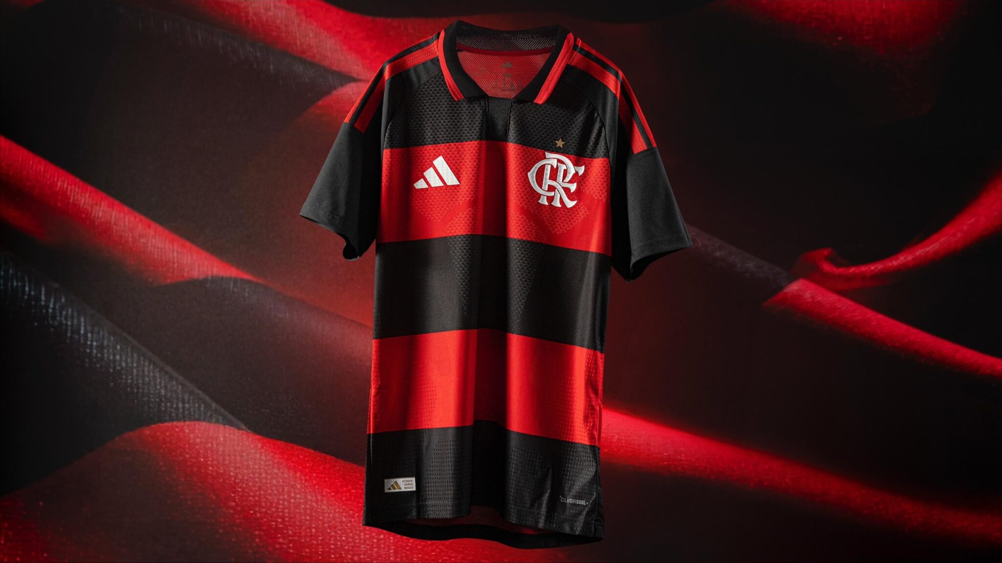 O novo Manto Sagrado do Flamengo é destaque, com design que remete aos anos 80, combinando tradição e tecnologia para a temporada. Camisa Flamengo listrada preta e vermelha, logos Adidas e CRF brancos, gola polo, estrela, etiqueta ClimaCool.