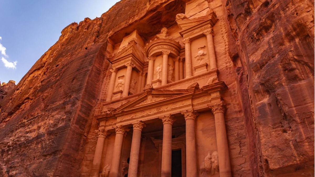Entre as sete maravilhas modernas, as ruínas de Petra na Jordânia exibem a grandiosidade da civilização nabateia. Antiga fachada de arenito rosa esculpida na rocha em Petra, Jordânia sob céu claro.