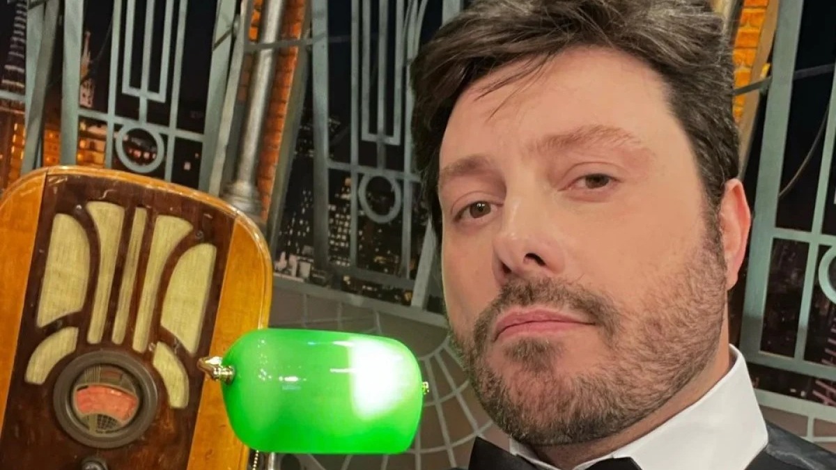 Danilo Gentili, apresentador mencionado por Luiza Ambiel sobre affair do passado, em um momento de sua aparição pública. Foto: Reprodução/Instagram Danilo Gentili posa de barba e camisa social, com rádio antigo e luminária verde