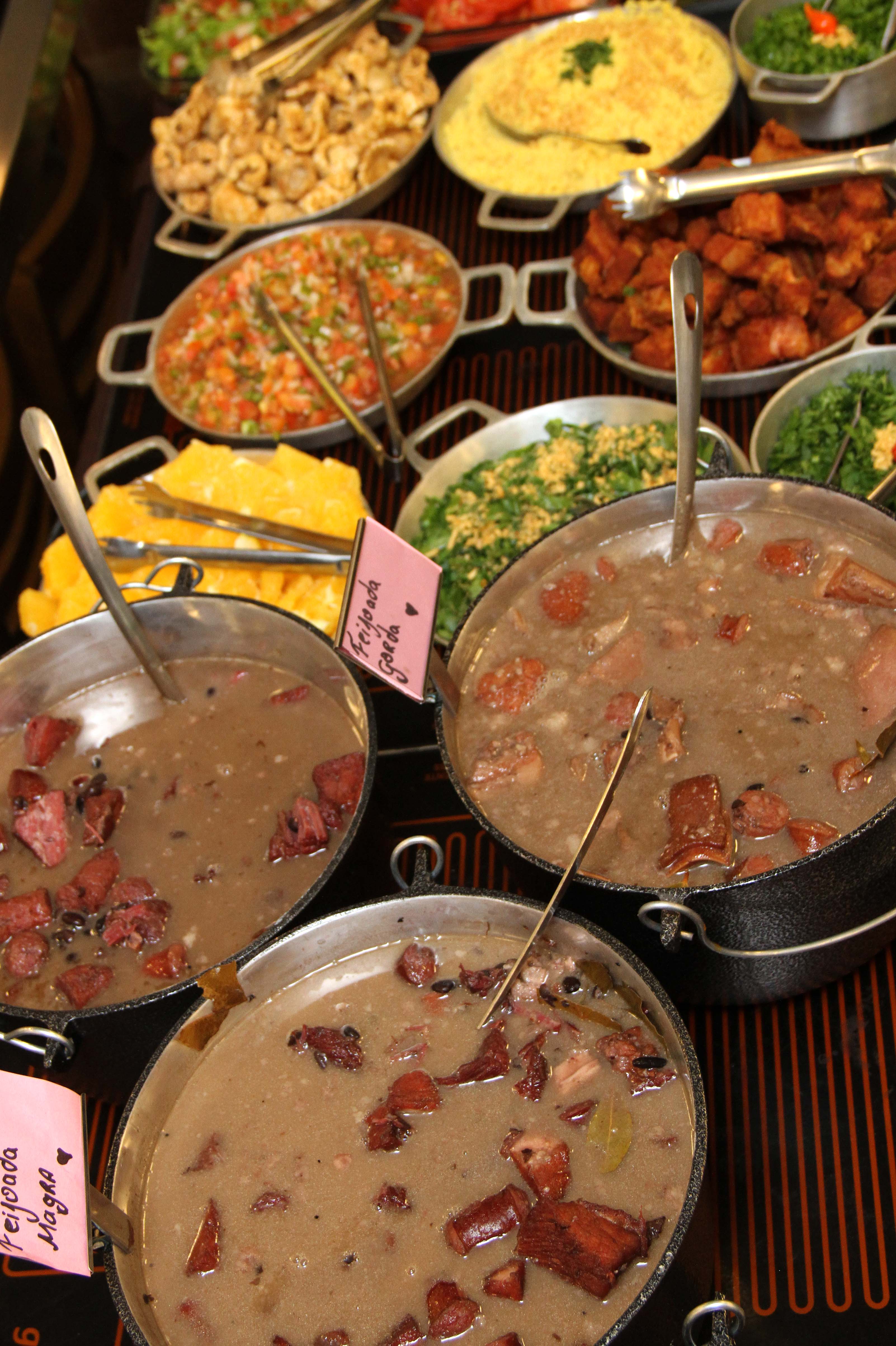 Panelas de feijoada com acompanhamentos 