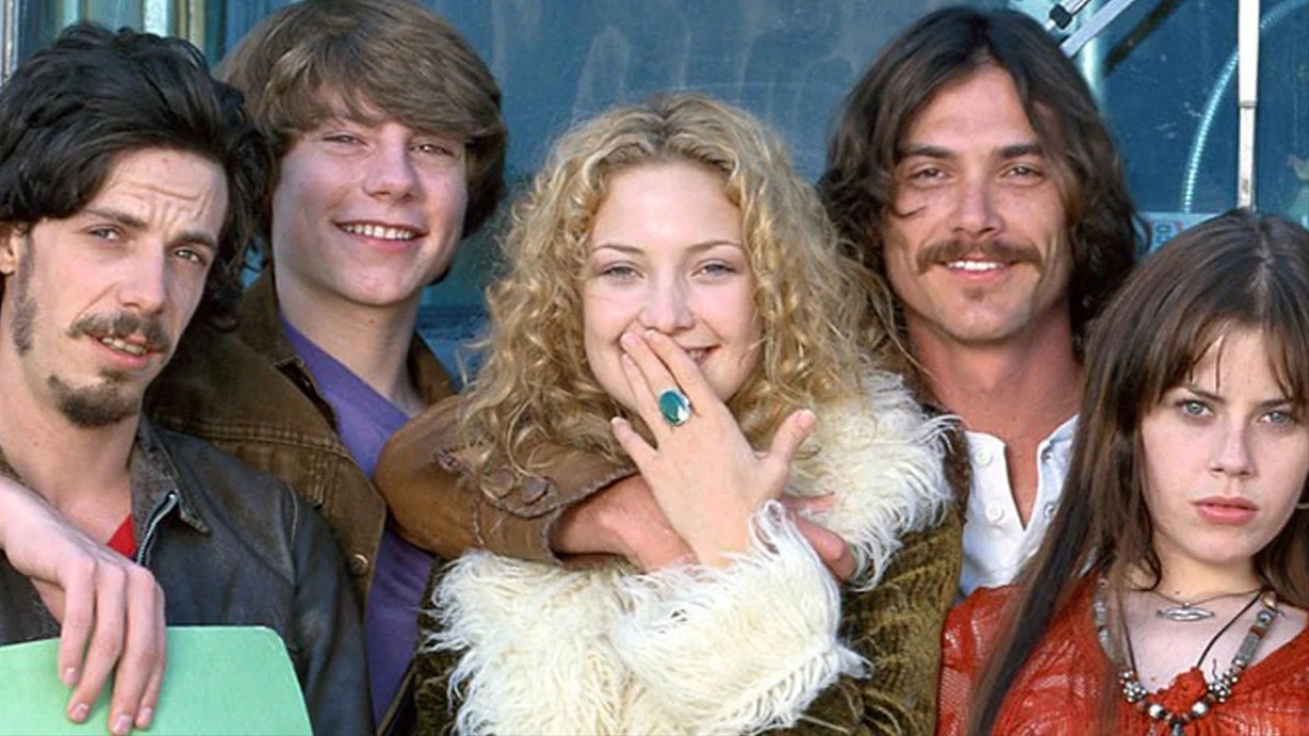 O elenco de "Quase Famosos", filme que retrata o universo do rock nos anos 70, é uma das sugestões para os dias de frio. Cinco atores jovens em estilo anos 70, com cabelo comprido e roupas coloridas, posam.