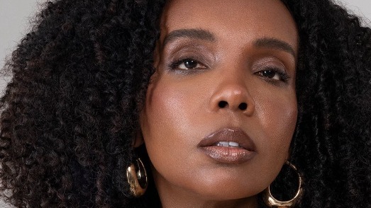 Thelma Assis, campeã do BBB 20, usou sua visibilidade para construir uma carreira de sucesso na comunicação e medicina. Close-up retrato de Thelma Assis, mulher negra com cabelo crespo e argolas douradas.