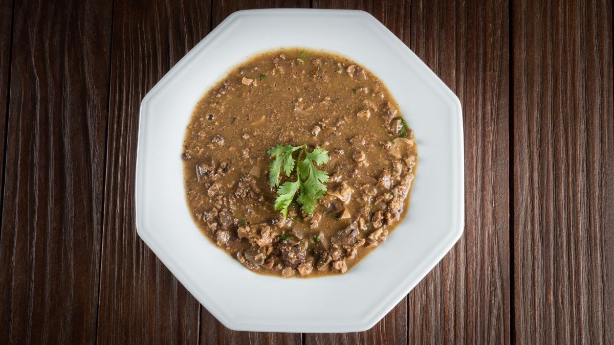 O sarapatel, com seus sabores intensos e preparo robusto, é uma das opções da culinária baiana para aquecer e confortar nos dias mais frescos. Prato branco octogonal com sarapatel cremoso e pedaços de carne, guarnecido com coentro.