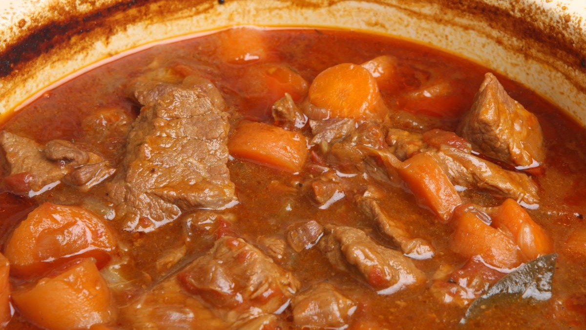 Pratos quentes e encorpados, como este ensopado de carne, são a pedida ideal para aquecer o inverno mineiro. Cozido robusto com pedaços de carne, cenouras em molho vermelho denso dentro de panela.