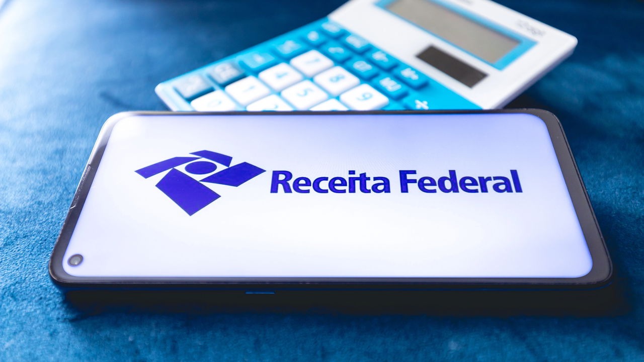 A Receita Federal e uma calculadora ilustram a gestão de recursos e cálculos financeiros nos pagamentos de atrasados do INSS. Smartphone exibe logo e nome "Receita Federal", com calculadora azul desfocada atrás.