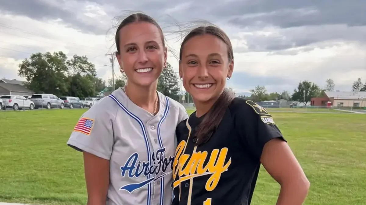 Samantha Rensvold e Kyann Dean, as irmãs que se reencontraram em um torneio de softball nos Estados Unidos. - Foto; Reprodução/Redes Sociais Duas jovens sorrindo em uniformes de softball 'Air Force' e 'Army' em campo gramado.