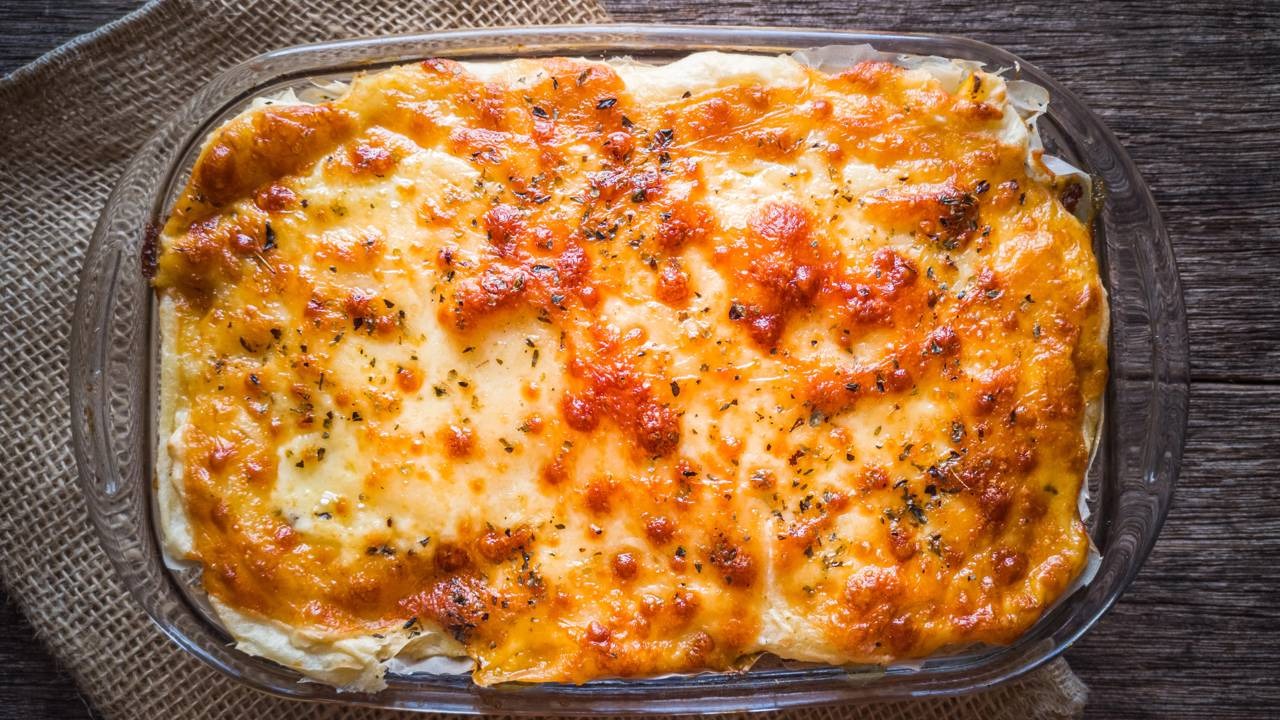 O escondidinho de carne moída e purê de batata finalizado com uma camada dourada de queijo gratinado, pronto para servir. Escondidinho de carne moída e purê de batata em travessa de vidro com queijo gratinado