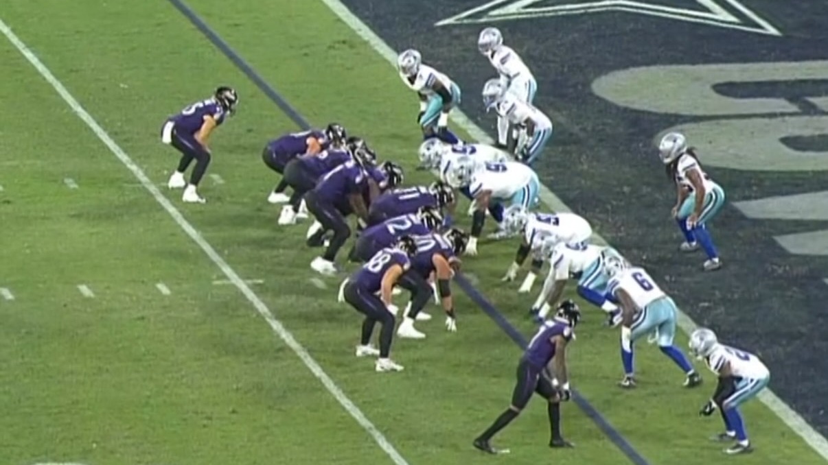 Jogadores do Baltimore Ravens e Dallas Cowboys se preparam para uma jogada na partida histórica da NFL no Maracanã. Jogadores do Ravens (roxo) e Cowboys (azul) alinhados para jogada em campo de futebol
