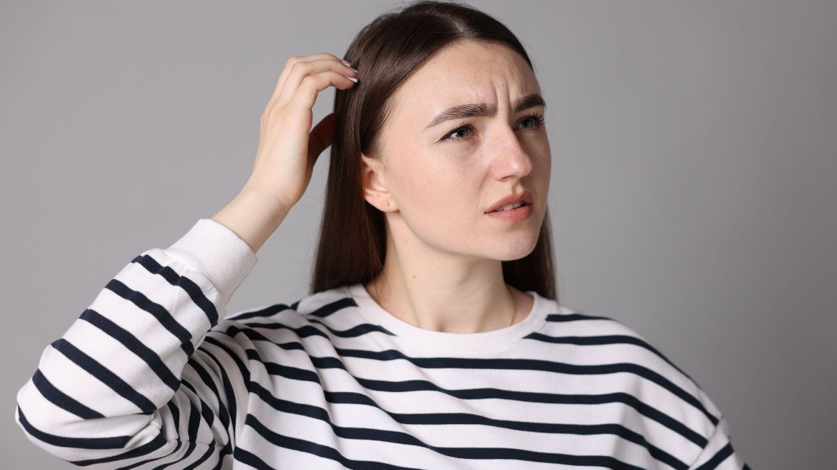 Esquecer palavras ou nomes é comum, mas conheça as dicas para fortalecer o cérebro. Mulher de blusa listrada, mão na cabeça, testa franzida, expressão de confusão.