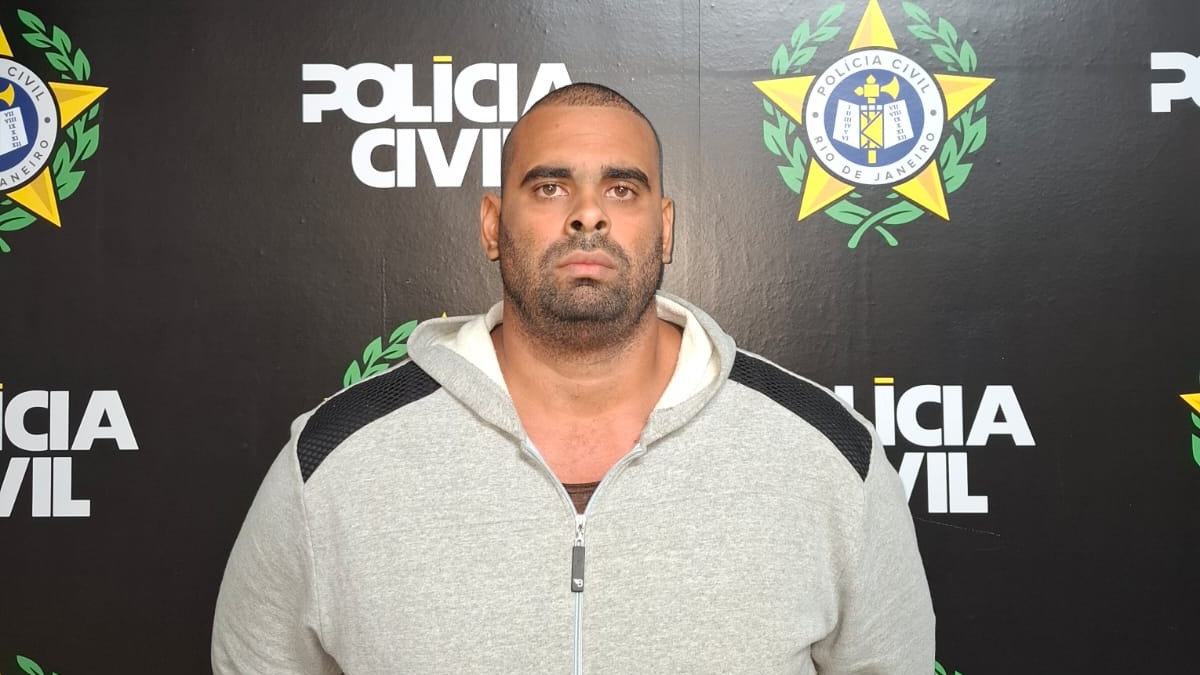 Diego Barbosa Guerra Mattos, preso pela Polícia Civil como autor do assassinato de sua mulher, Elaine Ferreira Ourique Mattos - Foto;Reprodução Homem de barba, cabeça raspada, moletom cinza, em fundo preto com logo da Polícia Civil