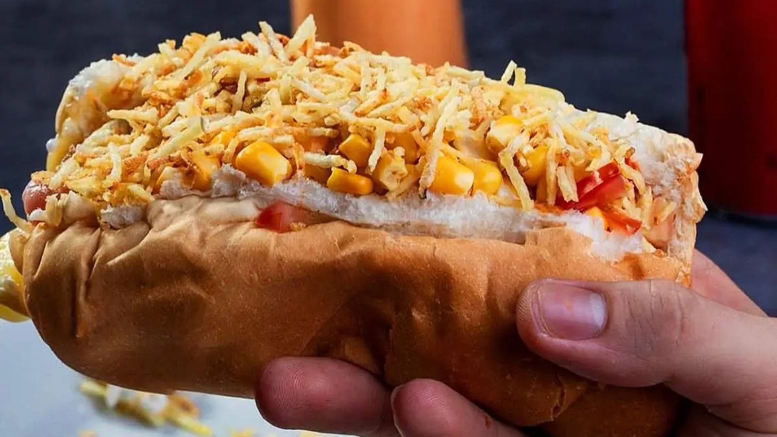 A versão paulistana do cachorro-quente, com purê de batata e batata palha, é um destaque da culinária de rua nacional Mão segura cachorro-quente brasileiro com batata palha, milho e purê de batata cremoso