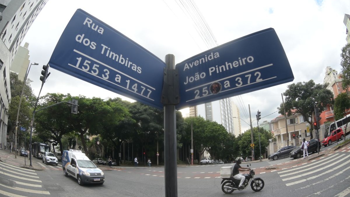Placas de rua das vias Timbiras e João Pinheiro em Belo Horizonte, que homenageiam povos originários e figuras históricas. Placa de rua dupla azul indicando "Rua dos Timbiras" e "Avenida João Pinheiro" em interseção.