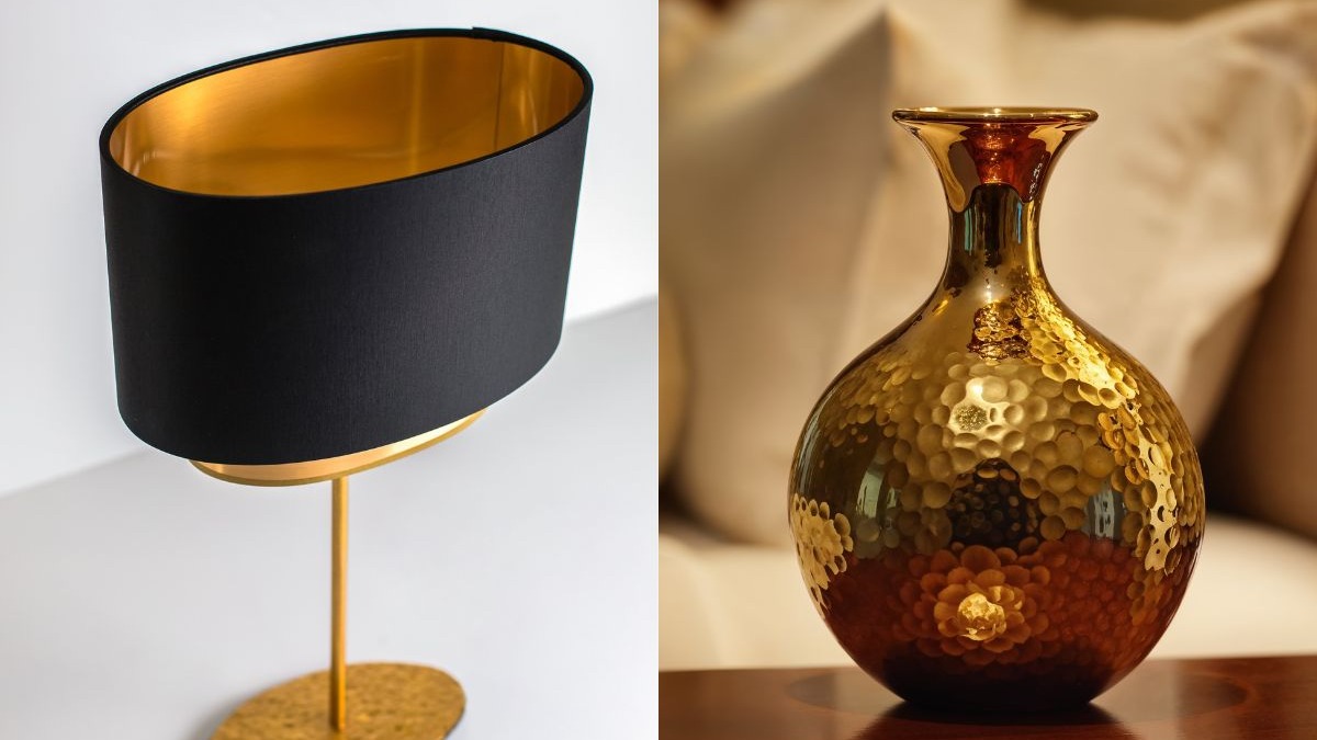 Lumin&aacute;ria de mesa com c&uacute;pula preta e interior dourado, ao lado de vaso dourado martelado.