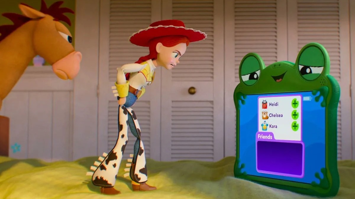 Jessie interage com um dispositivo eletrônico, tema central de "Toy Story 5" ao abordar o impacto da tecnologia no mundo dos brinquedos. Jessie e o cavalo Bullseye observam um tablet verde em formato de sapo com lista de amigos.