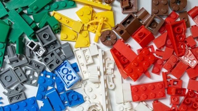 Pilha variada de pe&ccedil;as LEGO coloridas: verde, cinza, azul, branco, amarelo, marrom e vermelho.