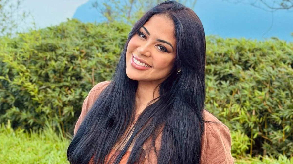 Gisele Nascimento, cantora gospel e mãe do jovem Israel, foi vítima das agressões que motivaram o crime no Rio de Janeiro - Foto; Reprodução Close-up de mulher sorridente com cabelo escuro comprido e jaqueta marrom, fundo verde borrado