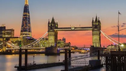 Londres oferece um cenário vibrante e multicultural, um dos atrativos para jogadores de elite em busca de qualidade de vida e excelência no futebol. Vista noturna da Tower Bridge e The Shard iluminados, com o rio Tâmisa ao entardecer.