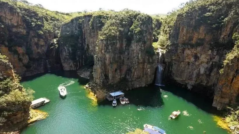 Passeios de lancha pelos cânions de Capitólio são o grande atrativo da região, conhecida como 'mar de Minas'. Cânions rochosos altos, lago verde-esmeralda, cachoeira e vários barcos em dia ensolarado.