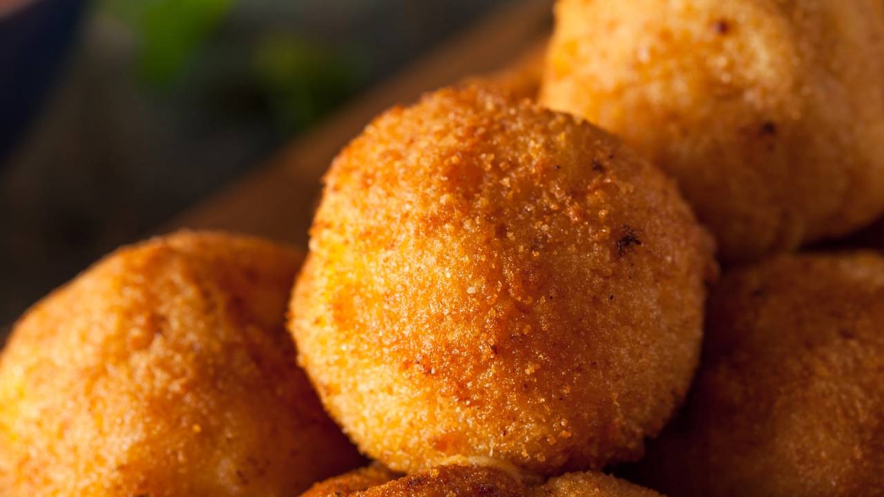 Descubra como a bolinha de queijo fit se torna a opção perfeita para um lanche saboroso e saudável. Close-up de várias bolinhas douradas de aparência crocante sobrepostas