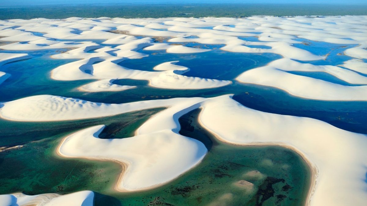 Vista a&eacute;rea de dunas de areia branca e lagoas de &aacute;gua azul e verde nos Len&ccedil;&oacute;is Maranhenses.