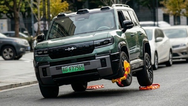 BYD Fang Cheng Bao Bao 8 é flagrado em Jinshan circulando com roda suspensa para contornar trava-rodas SUV verde com roda dianteira esquerda levantada e trava-roda. Placa ?G F77565
