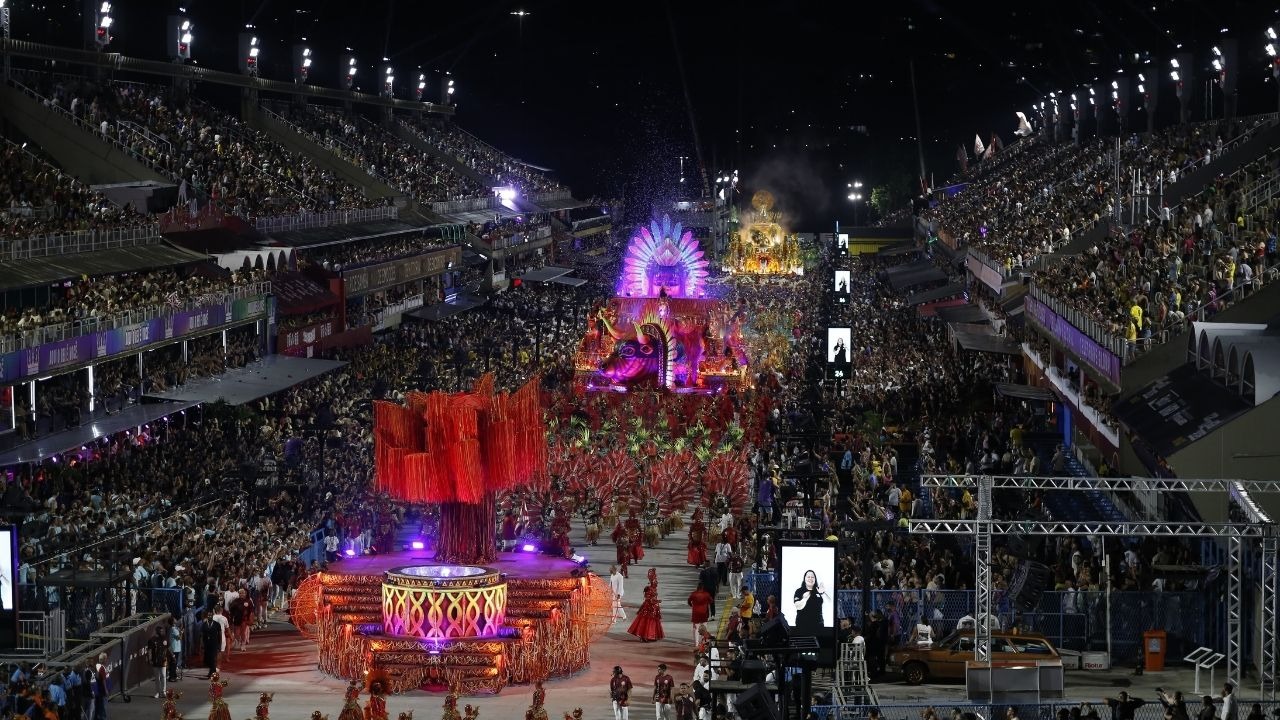 A Marquês de Sapucaí recebe os grandiosos desfiles de carnaval, para os quais a Liesa inicia nova fase de venda de ingressos Vista aérea noturna de desfile de carnaval na Sapucaí com carros alegóricos e arquibancadas lotadas