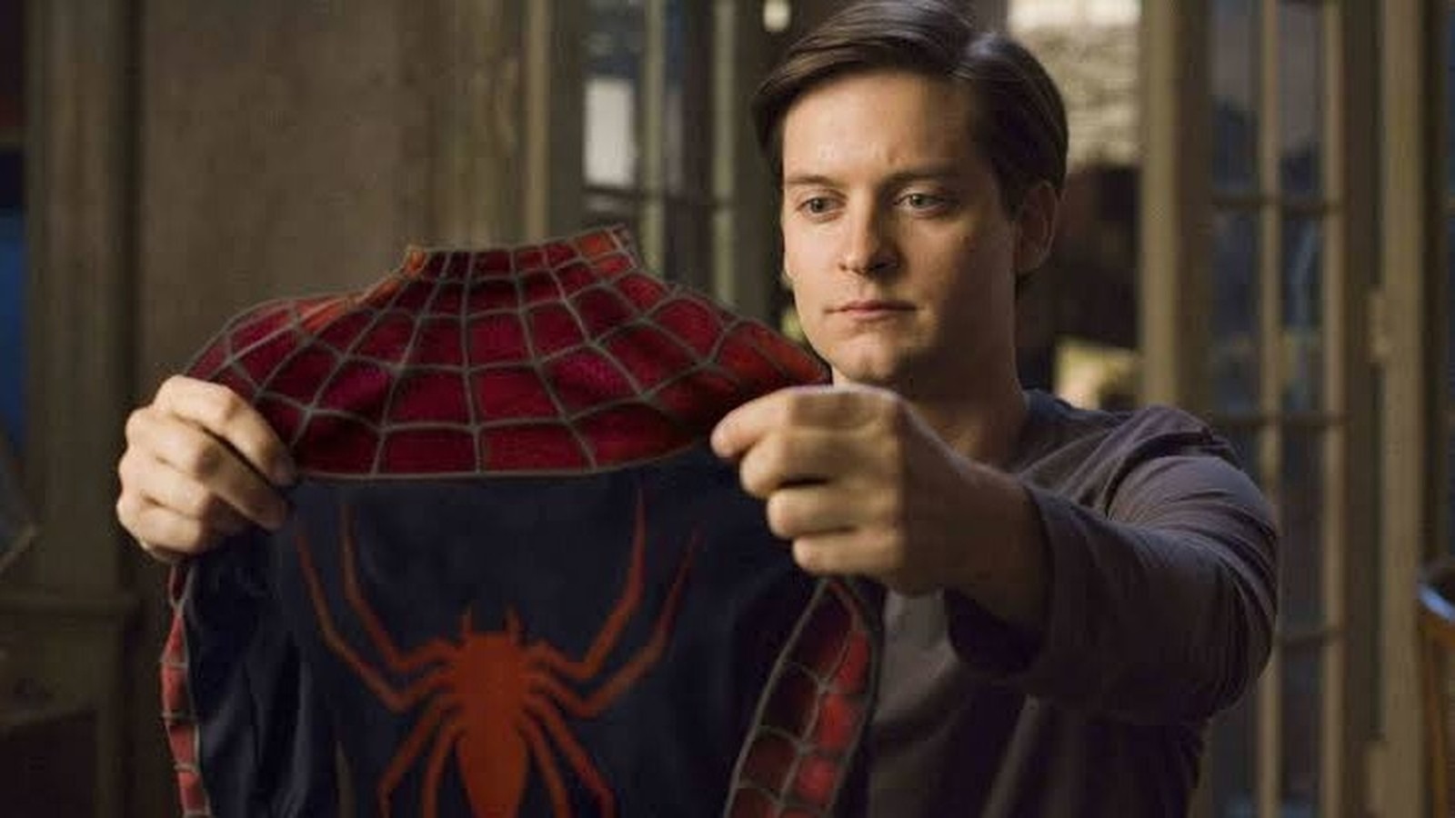 A saída da trilogia Homem-Aranha da Netflix exemplifica a dinâmica de licenciamento que afeta o catálogo das plataformas. Ator Tobey Maguire segura o traje vermelho e azul do Homem-Aranha, com logo de aranha nas costas