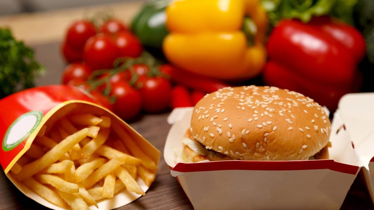 Aprenda a replicar o molho especial de fast-food, perfeito para valorizar lanches como hambúrgueres e batatas fritas. Hambúrguer com gergelim, batatas fritas em embalagem vermelha e vegetais frescos no fundo