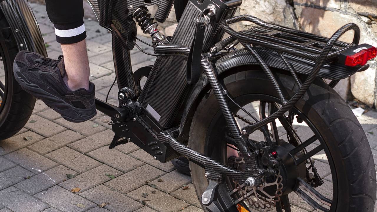 A regulamentação para o transporte de bicicletas elétricas nas barcas do Rio de Janeiro busca maior segurança. Perna e pé em pedal de bicicleta elétrica com padrão de fibra de carbono