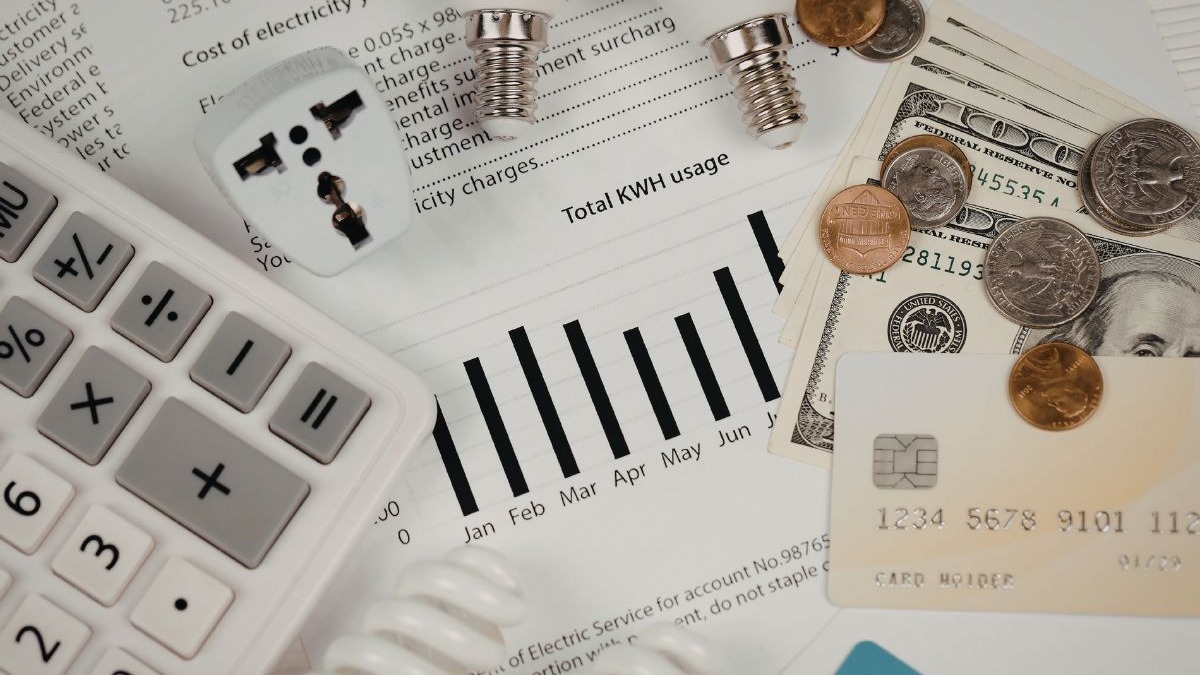 Calculadora, conta de luz, dinheiro, cart&atilde;o de cr&eacute;dito, plug e parafusos de l&acirc;mpada.