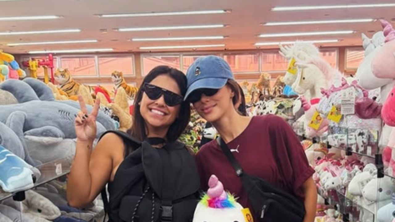 Bruna Biancardi na Rua 25 de Março para a maratona de compras da festa junina improvisada do jogador Neymar Duas mulheres sorridentes em loja de pelúcias, uma de boné azul e outra com óculos escuros