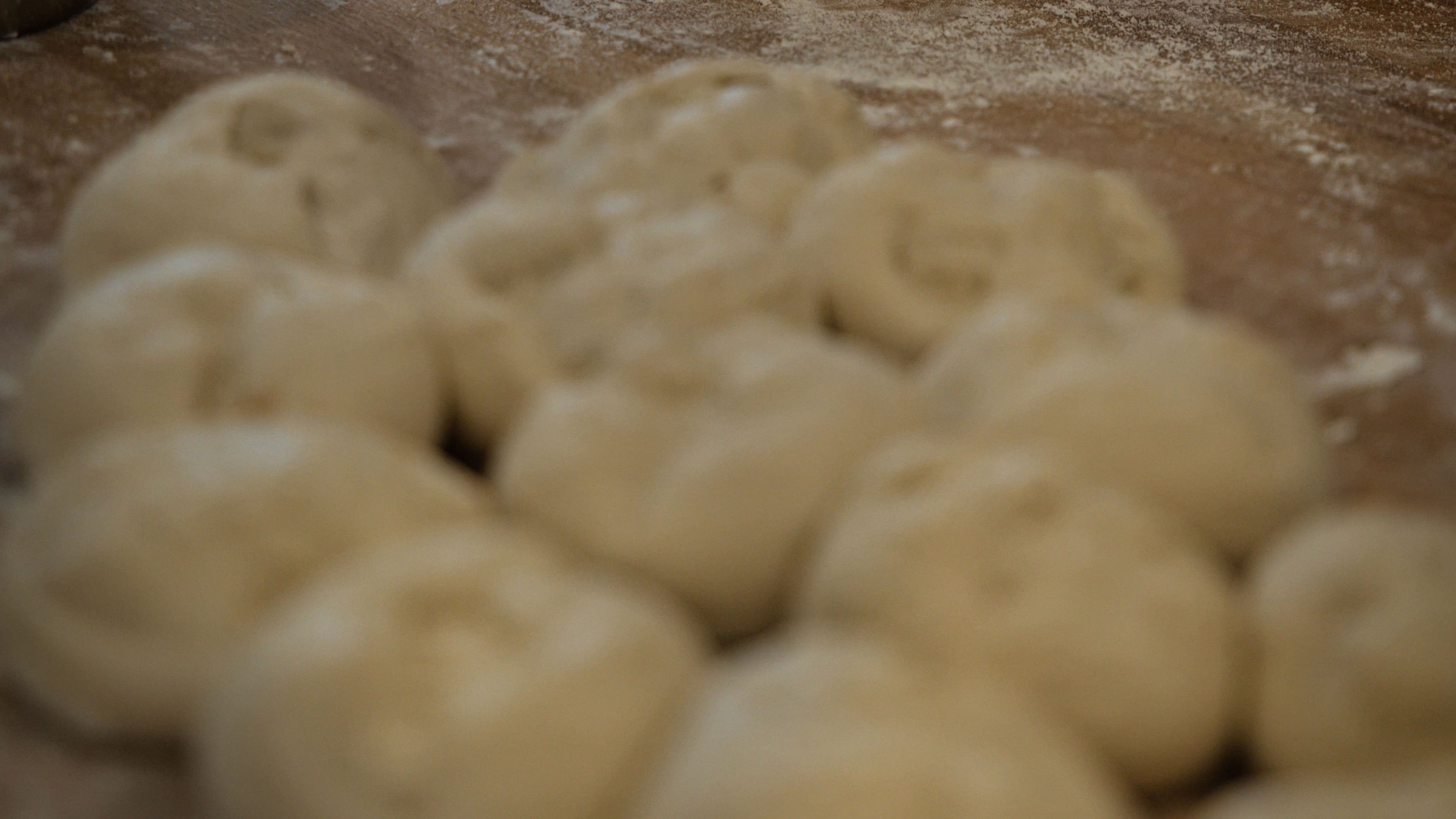 As bolinhas de massa para o preparo do pão no bafo, iguaria tradicional paranaense com influência alemã e cozida no vapor. Bolinhas de massa de pão crua com farinha em uma superfície de madeira.