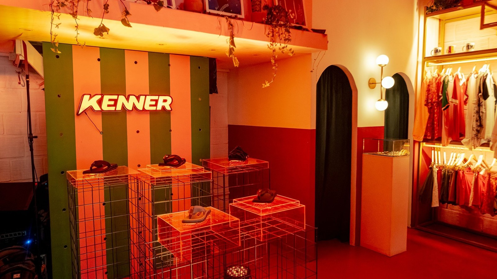 Placa neon 'KENNER' iluminada em loja com sand&aacute;lias expostas em pedestais de acr&iacute;lico
