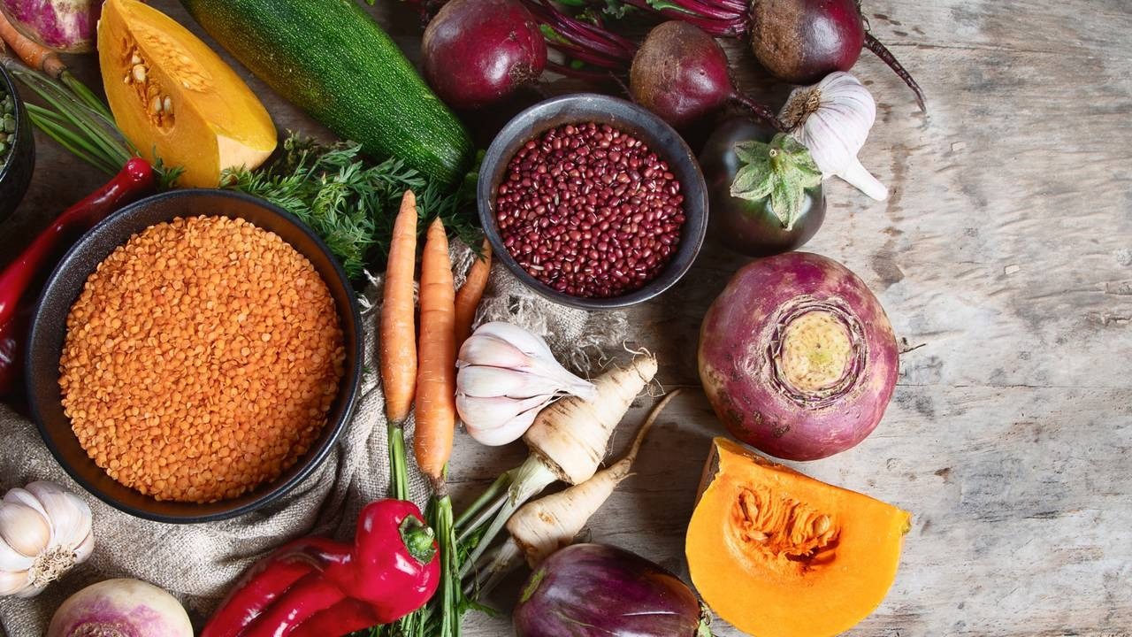 Seleção de vegetais frescos como abóbora, beterraba, cenoura, alho, e leguminosas em tigelas