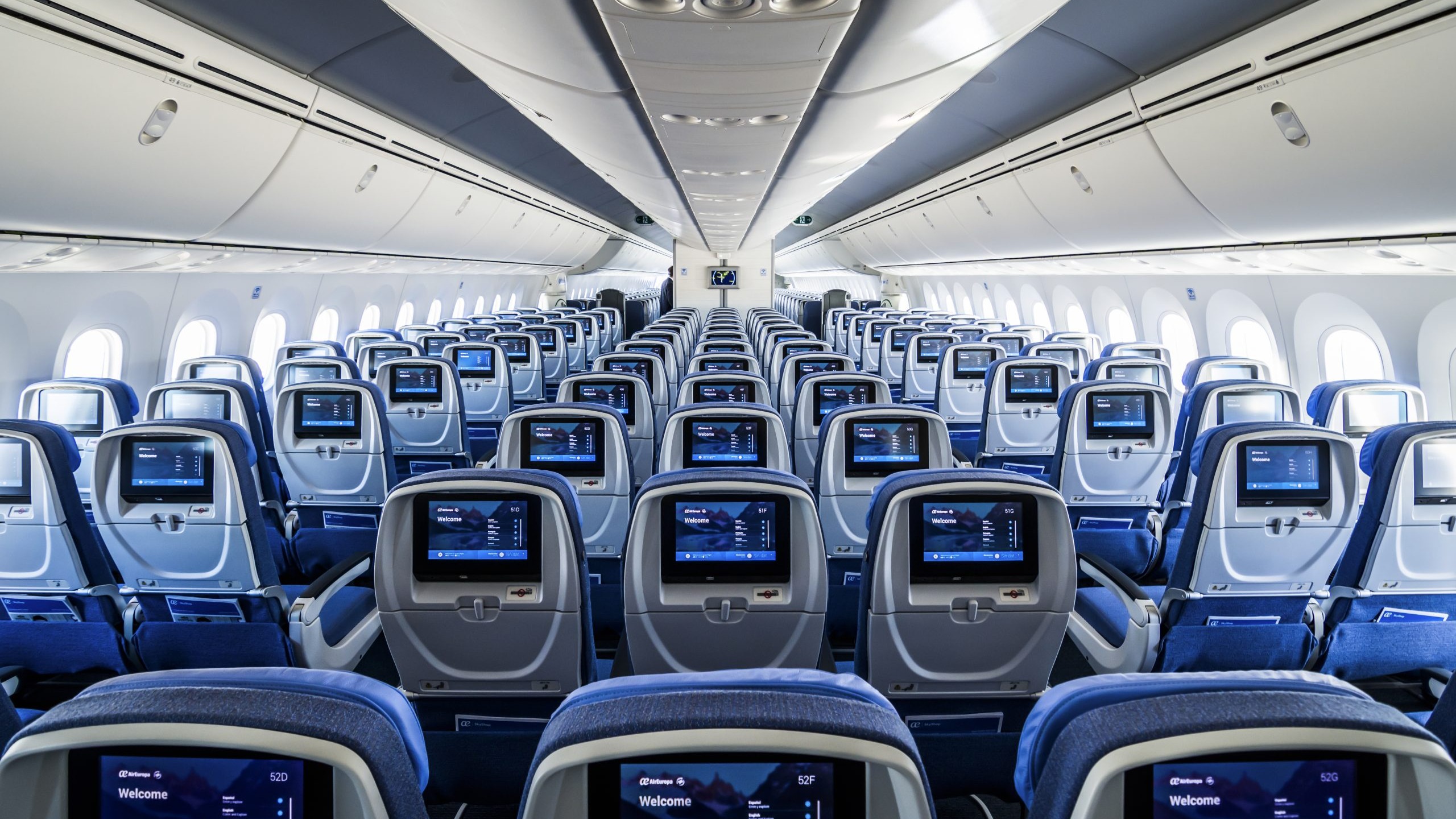 Interior de aeronave Boeing 787 Dreamliner vazia com fileiras de assentos azuis e telas individuais