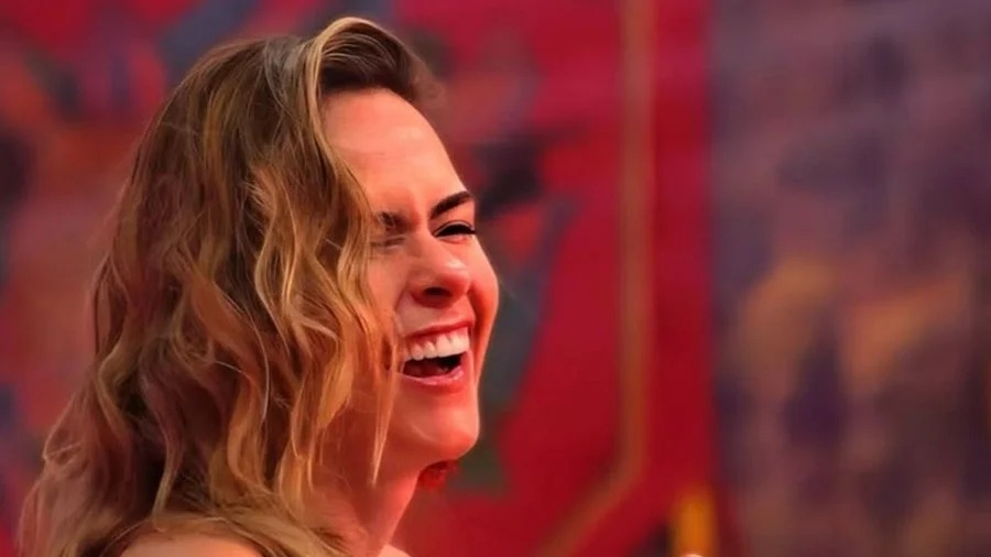 Com a personalidade forte que a tornou famosa, Ana Paula Renault retorna ao Big Brother Brasil para a 26ª edição. Ana Paula Renault rindo abertamente, com cabelos loiros ondulados, contra um fundo colorido e desfocado.