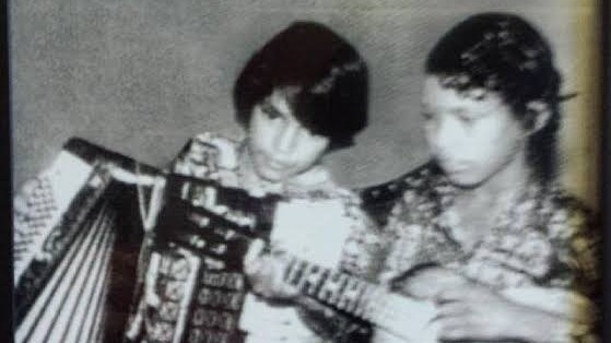 Dois meninos em preto e branco. Um toca acorde&atilde;o e o outro observa ao lado
