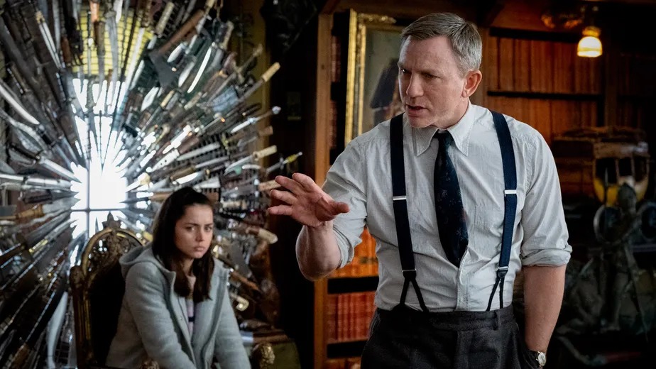 Daniel Craig e Ana de Armas em cena de "Entre Facas e Segredos", um dos filmes da lista para curtir o frio. Daniel Craig e Ana de Armas em cena do filme "Entre Facas e Segredos", com parede de facas.