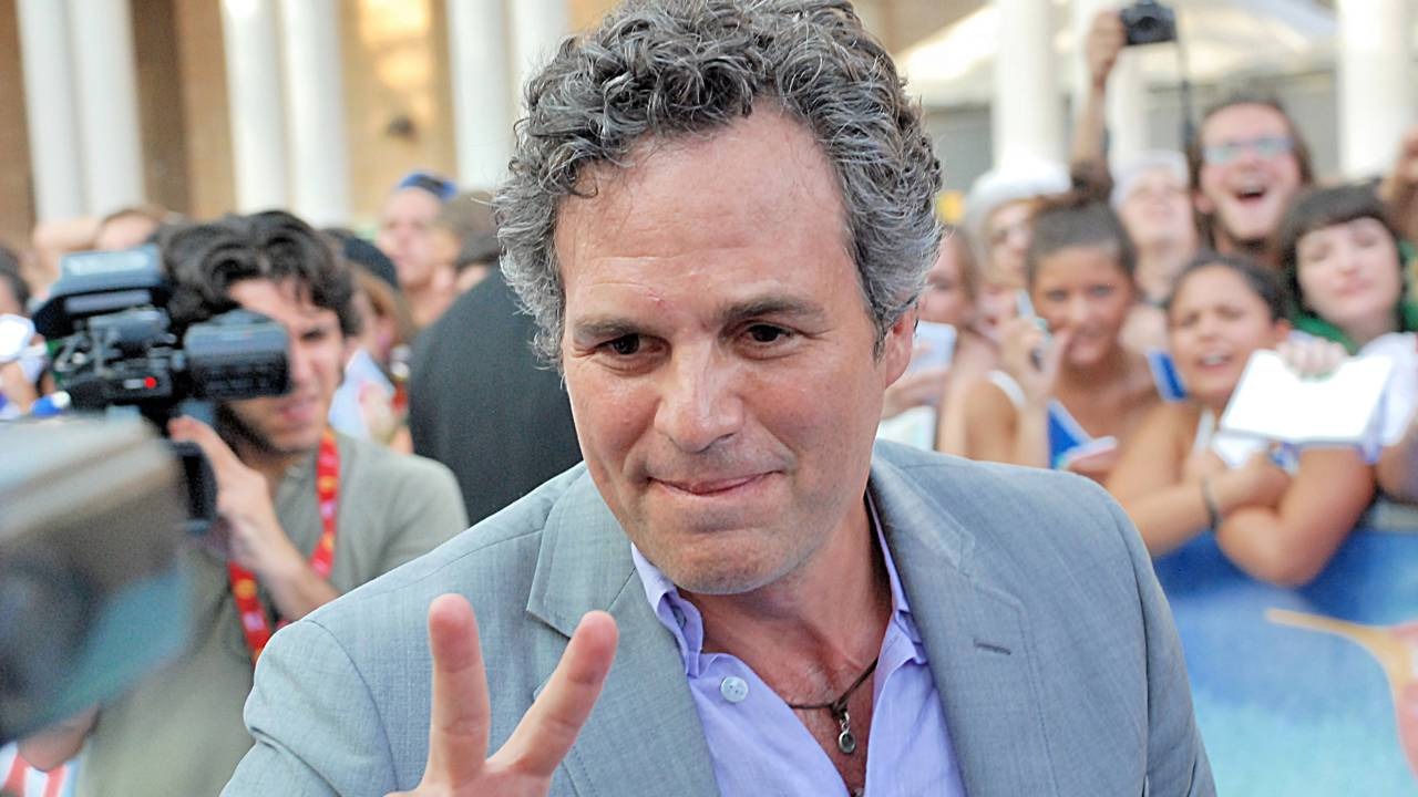 Mark Ruffalo, o Hulk do universo Marvel, que teve sua carteira perdida devolvida graças à mobilização de fãs nas redes sociais. Mark Ruffalo, sorrindo e fazendo sinal de paz, em meio a uma multidão de pessoas