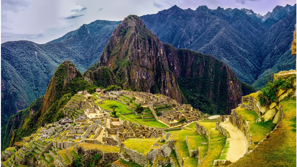 Machu Picchu, a "cidade perdida dos Incas" nos Andes, é destaque entre as maravilhas do mundo moderno. Ruínas incas de Machu Picchu com terraços verdes e montanhas íngremes sob céu nublado.