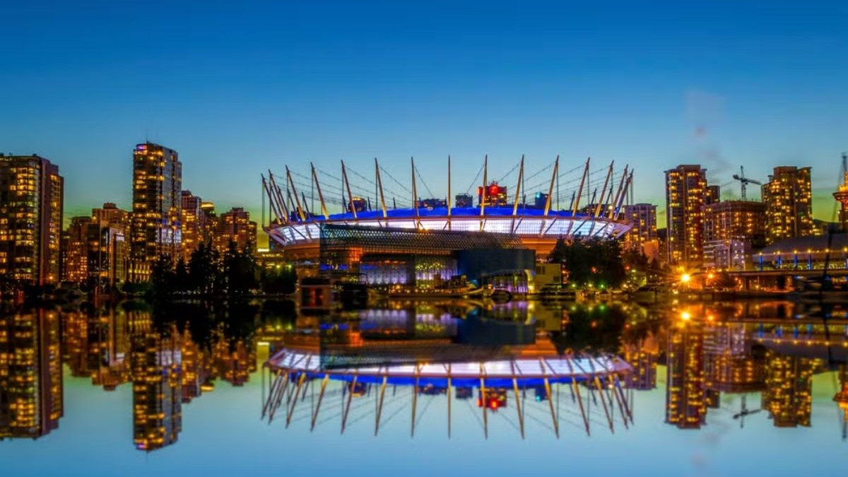 Canadá BC Place, em Vancouver Estádio BC Place iluminado à noite, refletido em água, com arranha-céus da cidade.