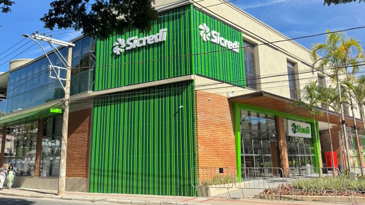 Edif&iacute;cio moderno do Sicredi com fachada verde, logo Sicredi, tijolos e janelas de vidro.