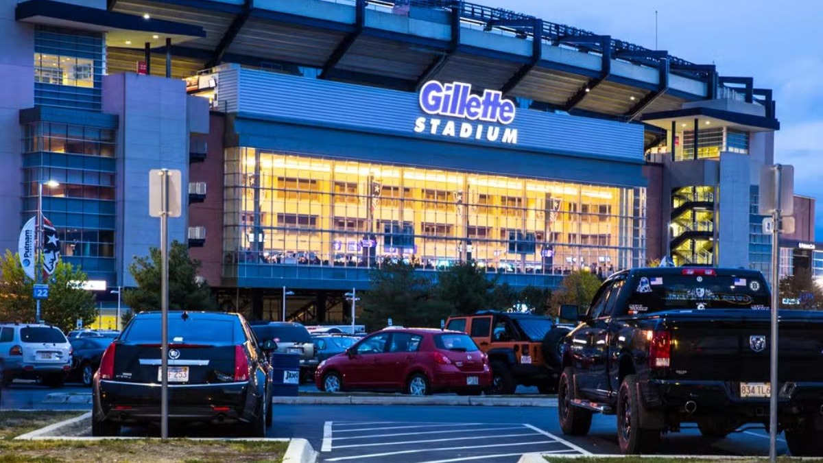 O Gillette Stadium, um dos modernos palcos esportivos dos Estados Unidos Fachada noturna do Gillette Stadium com letreiro iluminado e carros estacionados.