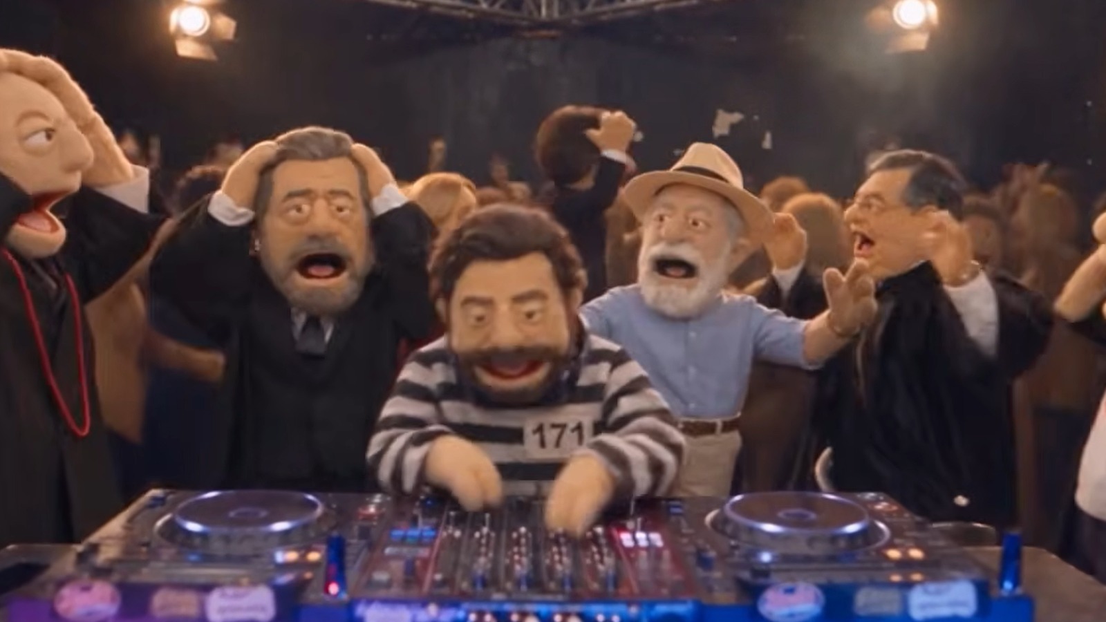 Bonecos fantoches de pol&iacute;ticos em festa, um DJ usa camisa listrada com 