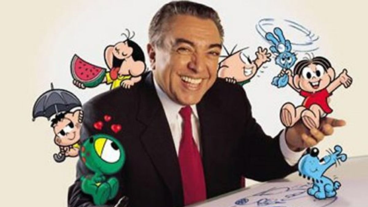 Mauricio de Sousa sorri cercado por Monica, Cebolinha, Magali e outros personagens da Turma da Mônica.