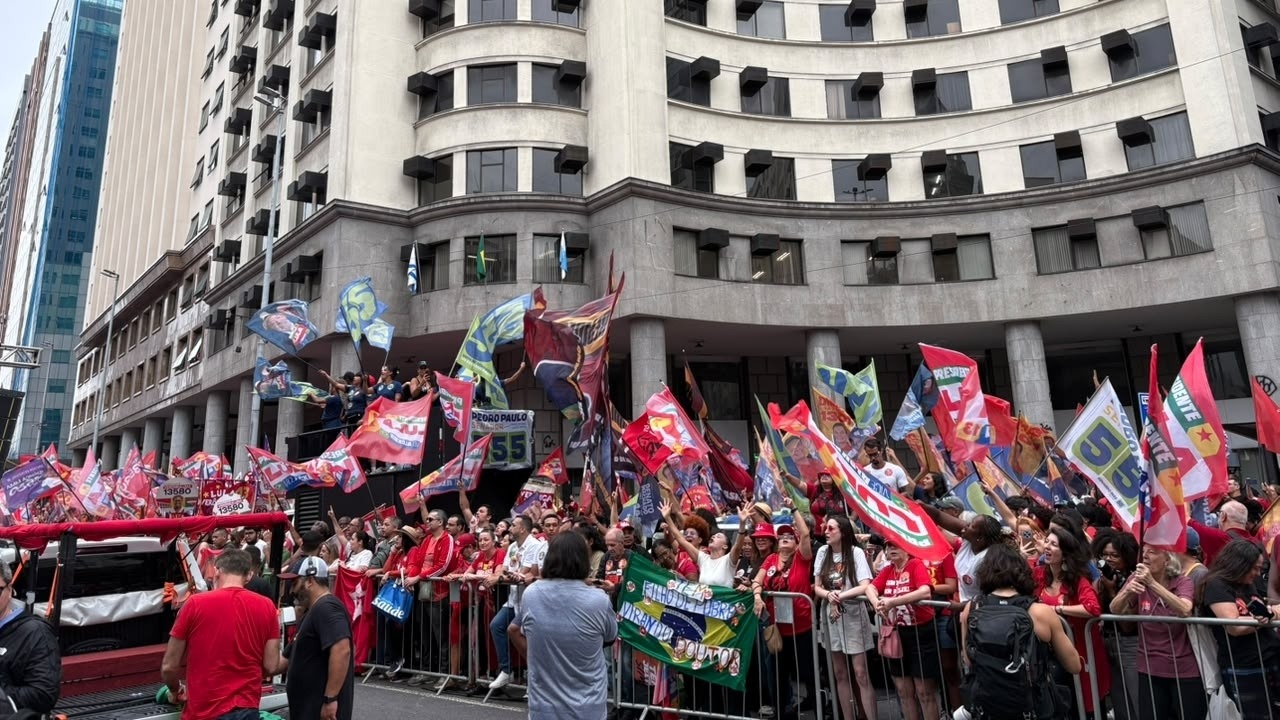 Apoiadores e militantes aglomeram-se em caminhada de campanha de Lula no Centro do Rio de Janeiro. - Foto: Lohrrany Alvim / Super Rádio Tupi Multidão com bandeiras vermelhas e de campanha "PRESIDENTE" e "55" no Centro do Rio.