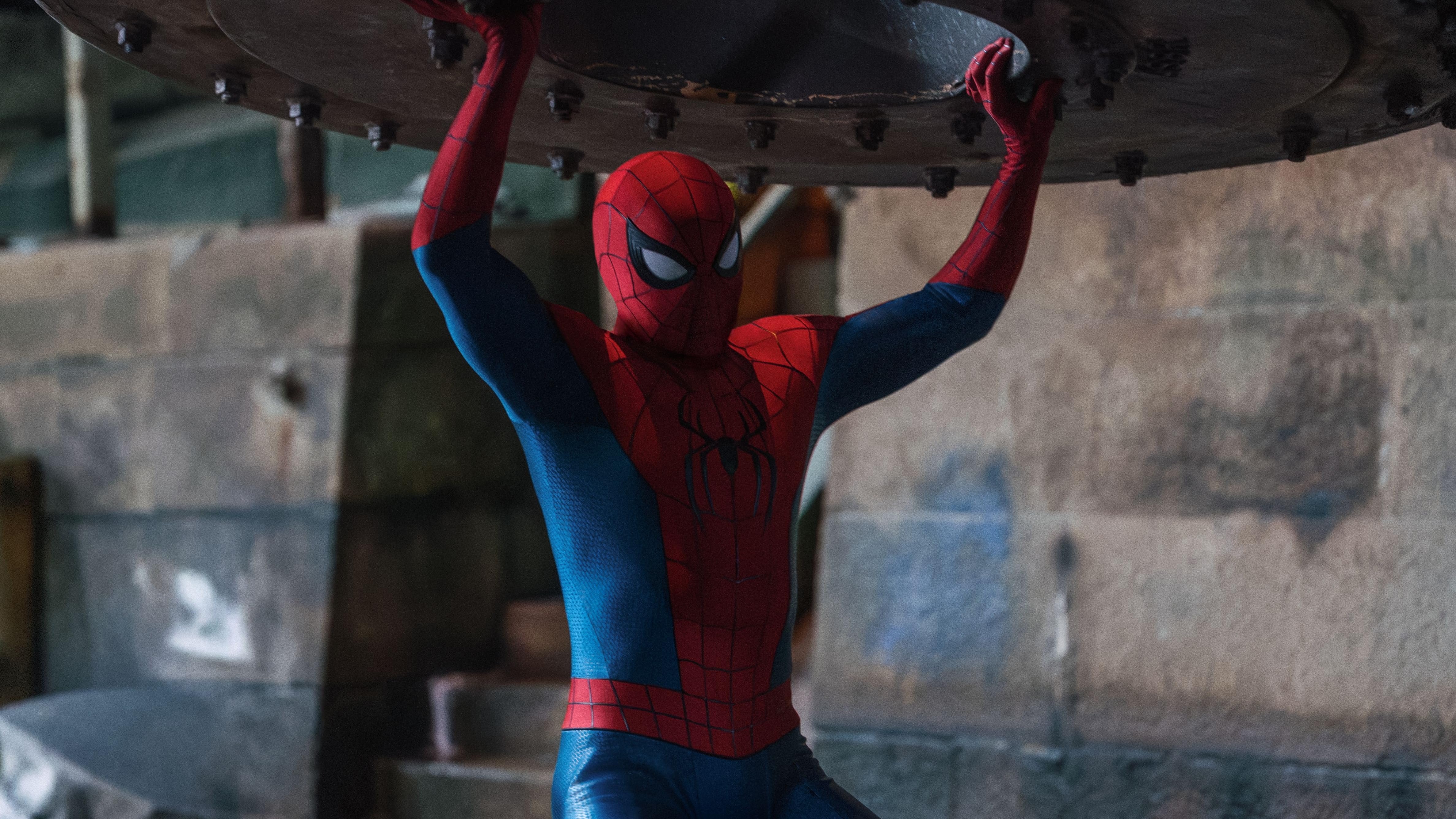 Após os eventos de ‘Sem Volta Para Casa’, o Homem-Aranha enfrenta desafios cada vez maiores na Saga do Multiverso. Homem-Aranha em traje vermelho e azul segura objeto metálico escuro, braços levantados em esforço
