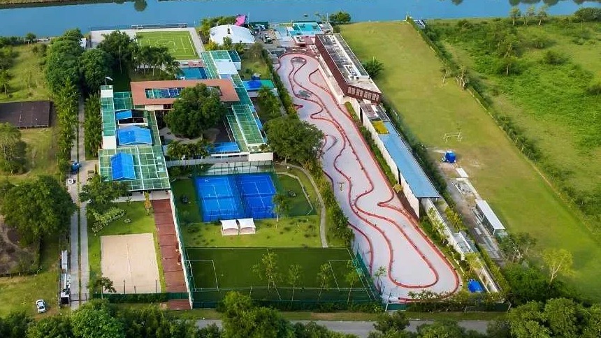 Vista aérea de complexo residencial com pista de kart, quadras esportivas, piscina e rio
