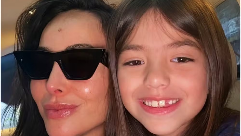 Sabrina Sato e a filha Zoe em momento de carinho, enquanto a apresentadora se emociona com o crescimento da primogênita. Close-up de mulher morena de óculos escuros e menina morena sorrindo com dente faltando